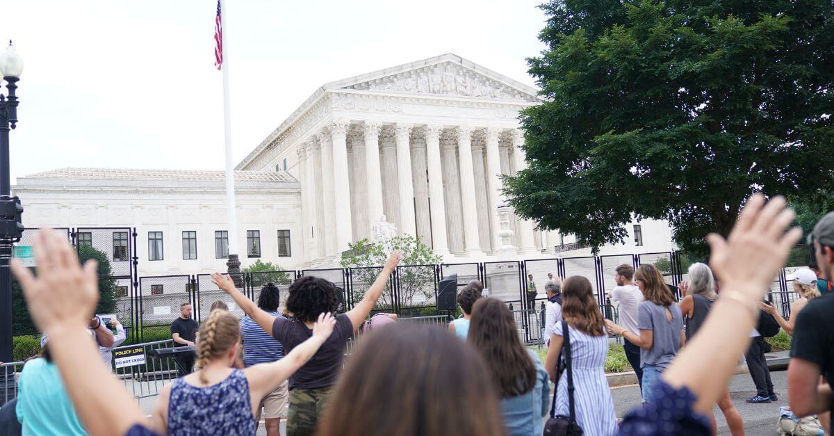 People pray outside the U.S. Supreme Court in June 2022 following its decision in <i>Kennedy v. Bremerton School District</i>. The Supreme Court ruled that a Washington state high school football coach had a right to pray on the field immediately after games.