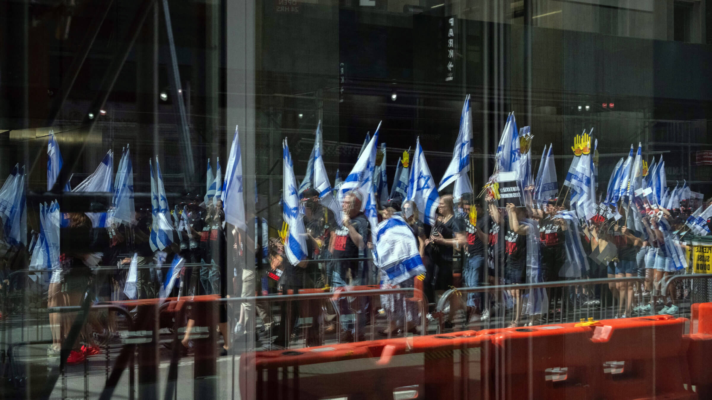 People holding Israel flags are reflected in a window before the Israel Day on Fifth parade on June 2, 2024 in New York City.