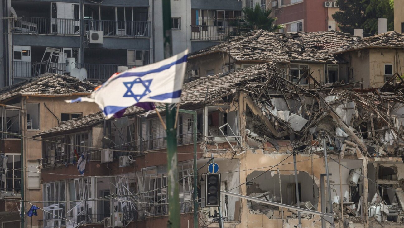 The Israeli flag flutters in front of a destroyed building at the site of an Iranian missile attack in Ramat Gan in central Israel near Tel Aviv, on June 19, 2025.