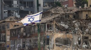 The Israeli flag flutters in front of a destroyed building at the site of an Iranian missile attack in Ramat Gan in central Israel near Tel Aviv, on June 19, 2025.