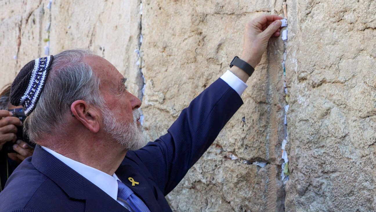 The US' ambassador to Israel Mike Huckabee places a note given to him from US President Donald Trump in the cracks of the Western Wall, the holiest site where Jews are allowed to pray, during Huckabee's visit to the holy site in the old city of Jerusalem on April 18, 2025.