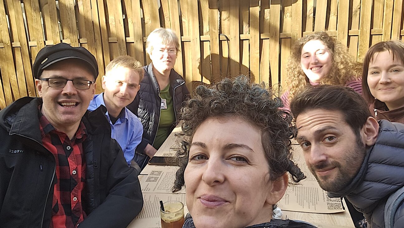 אַ גרופּע באַטייליקטע אין דער פּראָגראַם וואַרטן אויף אַ רומענישער מאָלצײַט אין אַן אָרטיקן רעסטאָראַן