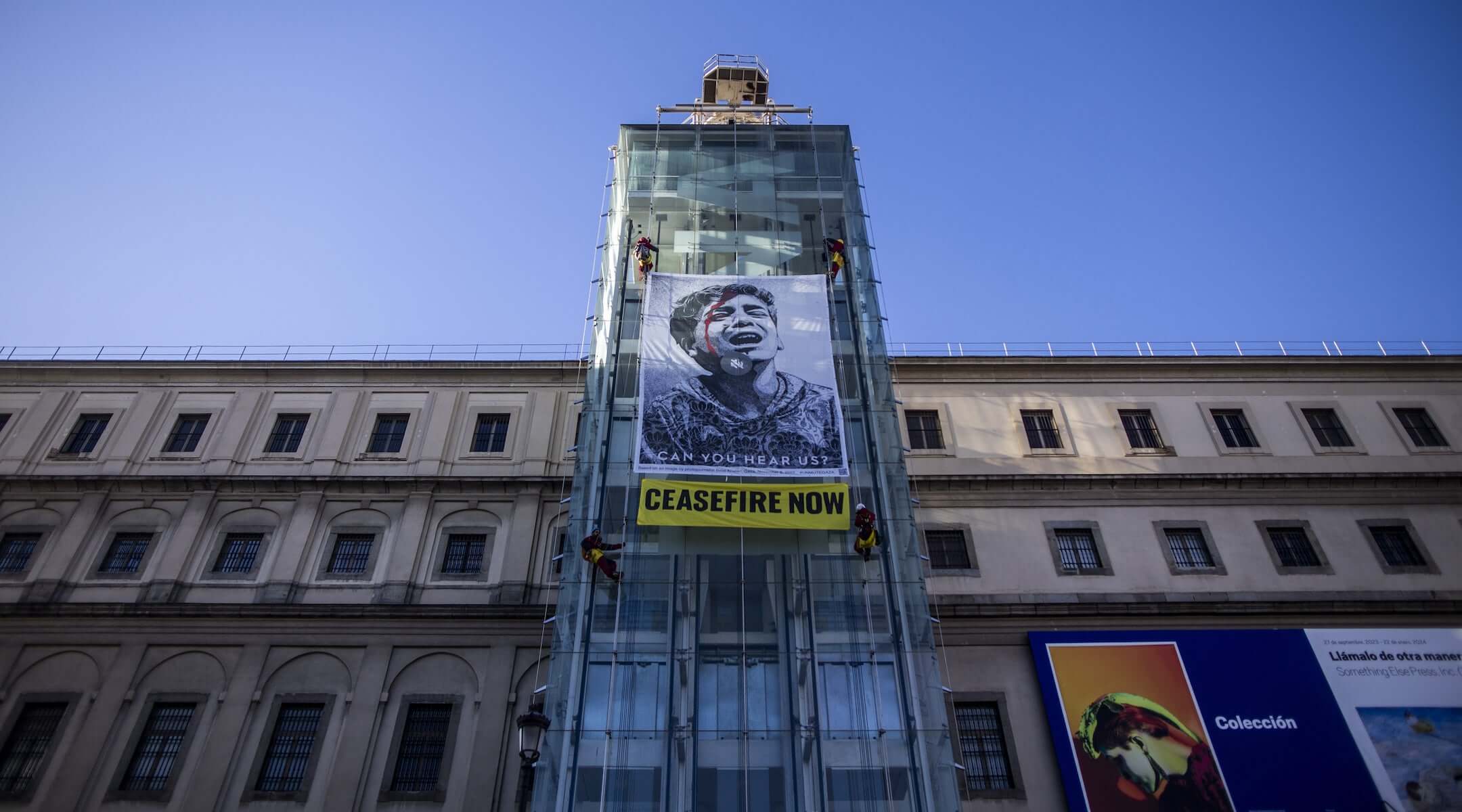 The international environmentalist organization Greenpeace uses a photograph from Gaza, taken by a Palestinian photojournalist, on a giant banner hung on the main entrance gate of the Reina Sofia Museum in Madrid, Spain on Jan. 24, 2024. (Bruno Thevenin/Anadolu via Getty Images)