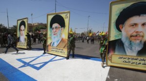 Portraits of Iran's Supreme Leader Ali Khamenei (center), his predecessor and Islamic Revolution founder Ayatollah Ruhollah (left) and late Iraqi Shiite cleric Mohammed Baqer al-Sadr with a slogan reading in Arabic : “He who accepts peace with Israel, is no more a Muslim,” are pictured during a military parade marking Al-Quds (Jerusalem) International Day in Baghdad, on May 31, 2019.