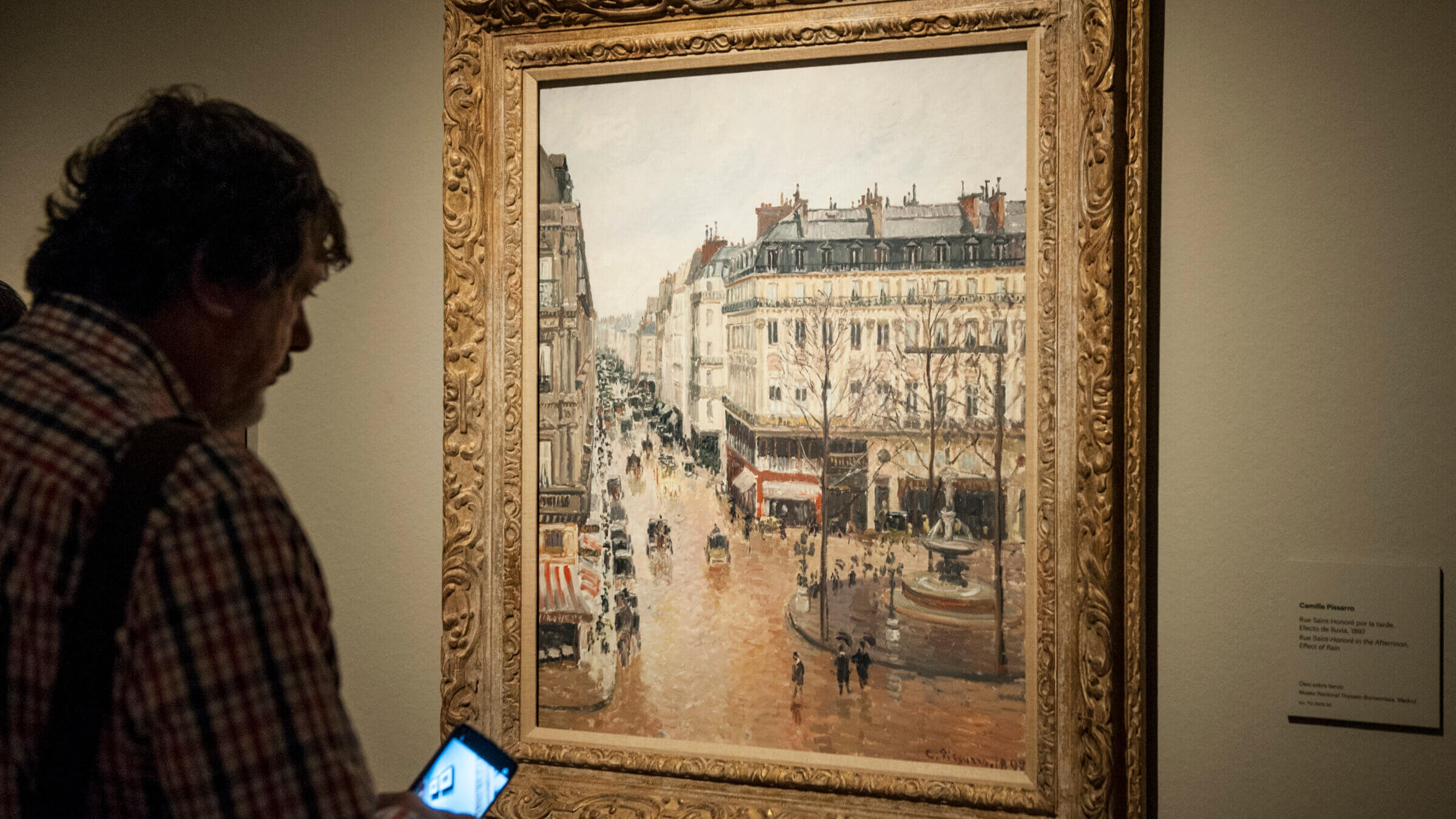 Museum goer looks at Pissarro's 'Rue Saint-Honore in the Afternoon. Effect of Rain' at the Thyssen-Bornemisza Museum in Madrid.