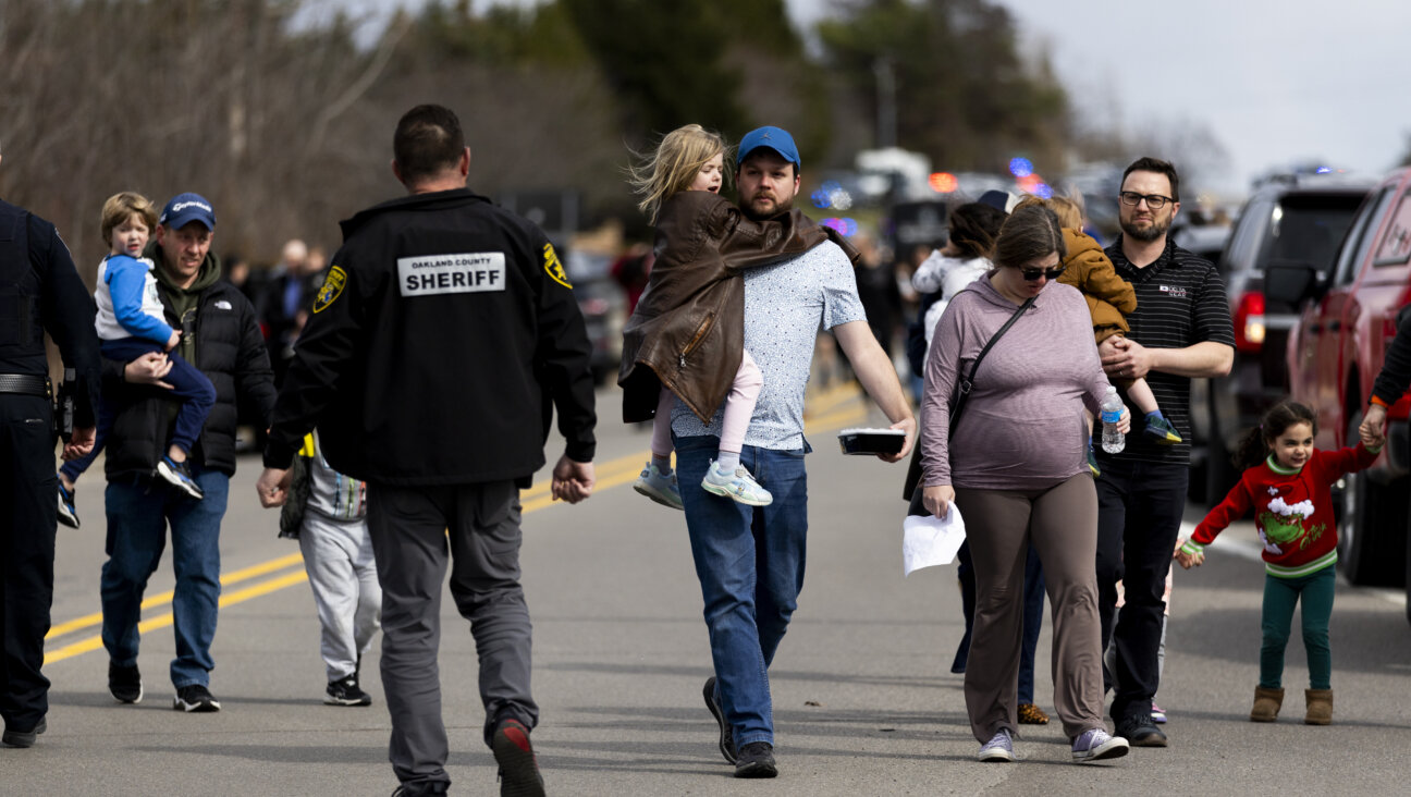 Parents carry their children to their cars as enforcement escorts families following an active shooter incident at Temple Israel in West Bloomfield, Michigan on Thursday.