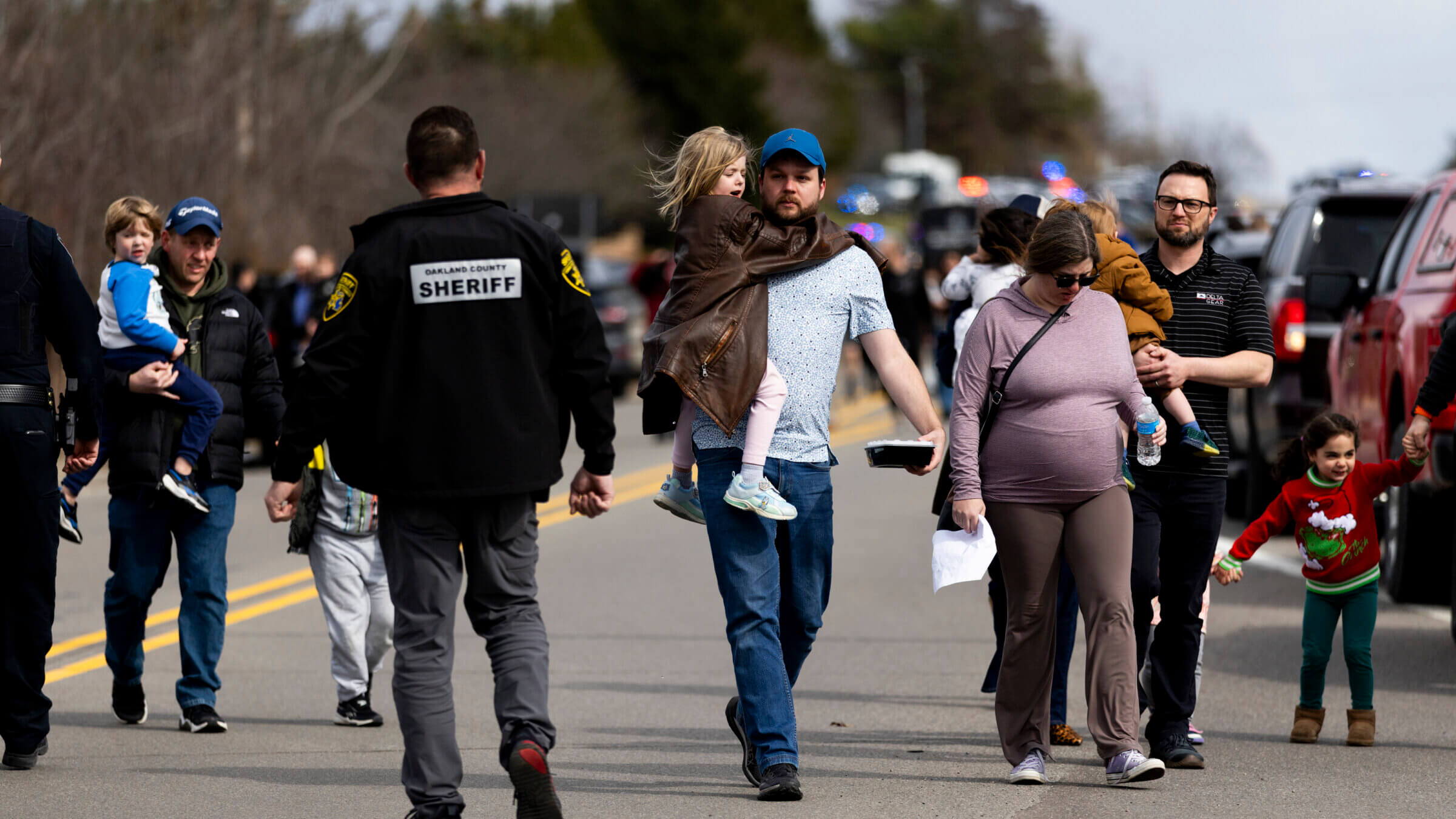 Parents carry their children to their cars as enforcement escorts families following an active shooter incident at Temple Israel in West Bloomfield, Michigan, on Thursday.
