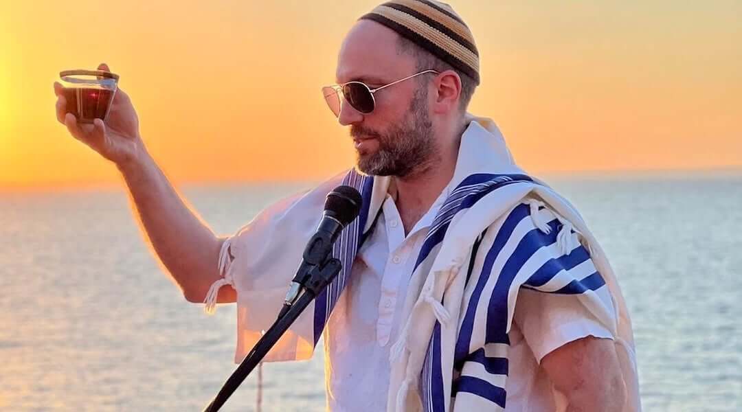 A rabbi raises a glass of kosher wine as he recites a blessing.