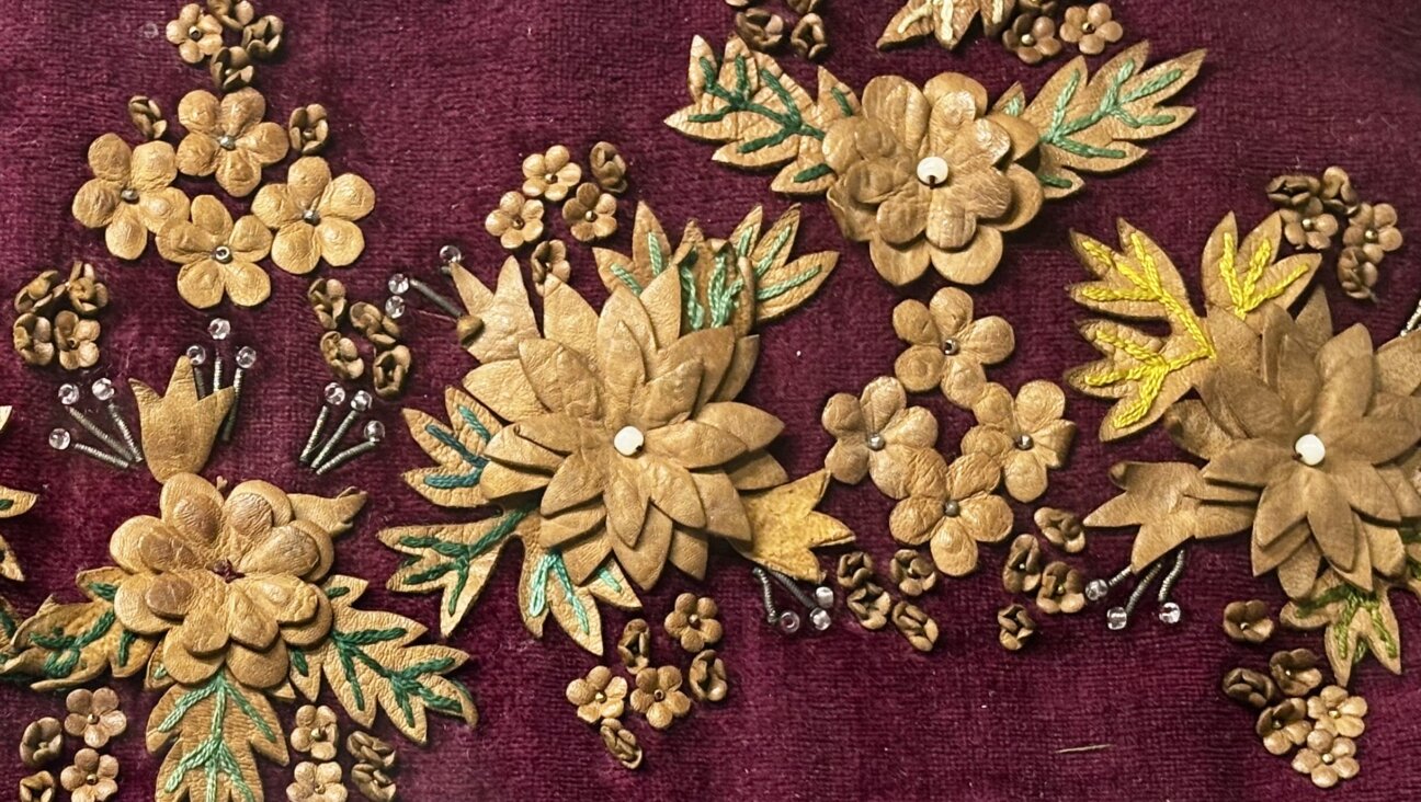 An intricately decorated 18th-century binder featuring intricate leatherwork flowers, embroidery and beads on plum-colored velvet.
