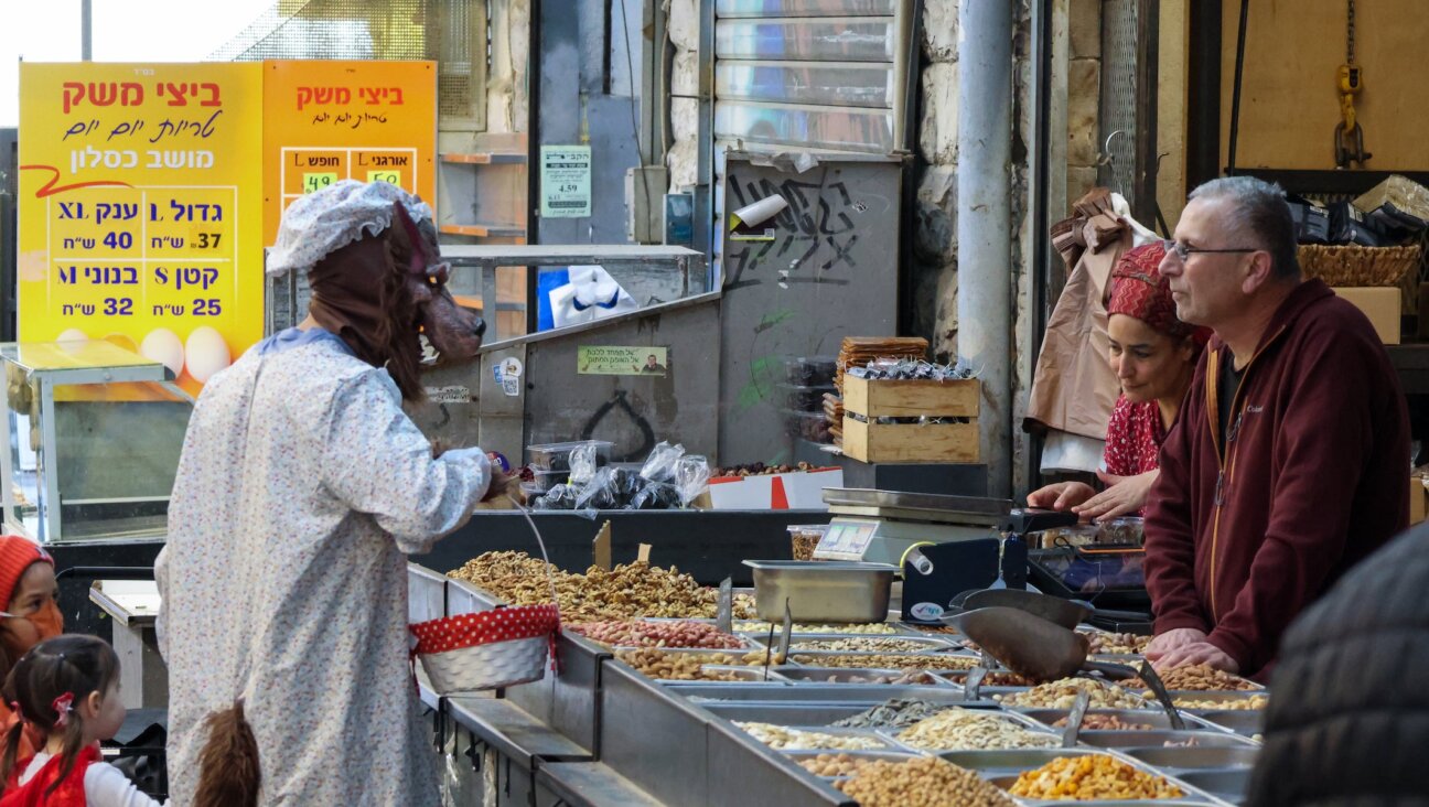 A man wearing a wolf costume with his daughter dressed as Little Red Riding Hood shops at a stall in the Machane Yeduda market in Jerusalem, which was operating at limited capacity because of the war with Iran, during Purim in Jerusalem, March 4, 2026.