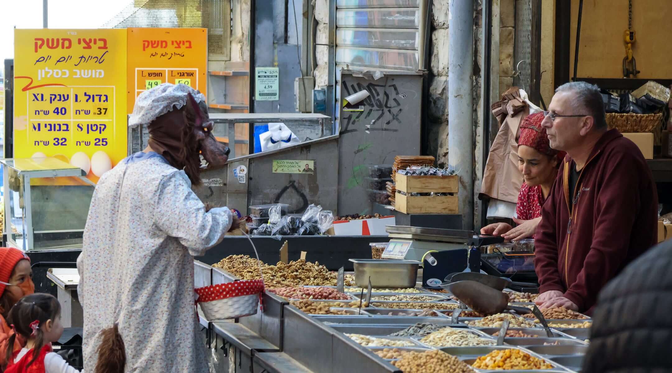 A man wearing a wolf costume with his daughter dressed as Little Red Riding Hood shops at a stall in the Machane Yeduda market in Jerusalem, which was operating at limited capacity because of the war with Iran, during Purim in Jerusalem, March 4, 2026.