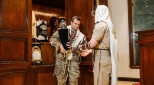 Jewish service members hold a torah scroll while wearing tefillin at the Aleph Institute's Military Symposium in February 2026.