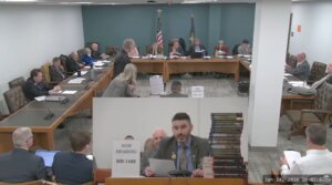 New Hampshire GOP state Rep. Matt Sabourin dit Choinière (center) testifies before a state committee on his proposed amendment to add a Holocaust denier to the state’s Holocaust education commission, Jan. 14, 2026. He is flanked by a stack of Holocaust-denial books. (Screenshot)
