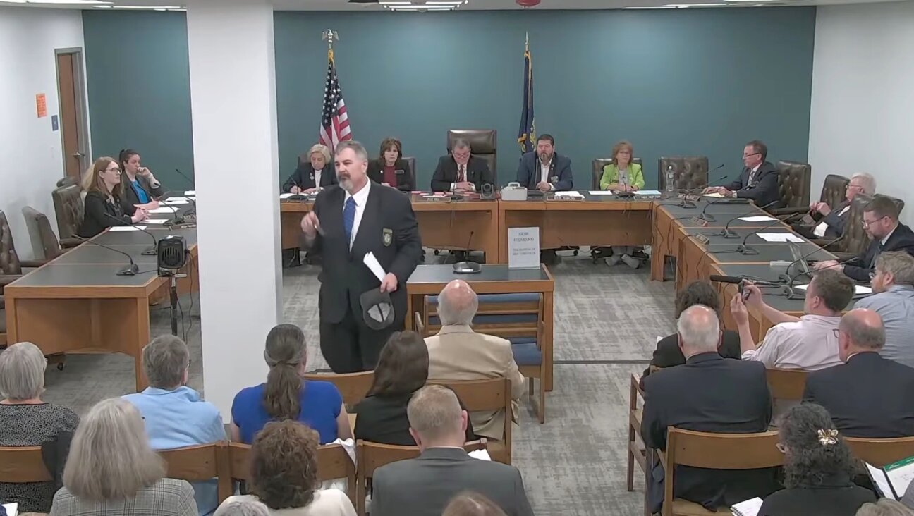 New Hampshire GOP state Rep. Travis Corcoran (center) walks out of his own disciplinary hearing for tweeting a “final solution” reference at a Jewish colleague, April 27, 2026. (Screenshot)