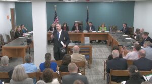 New Hampshire GOP state Rep. Travis Corcoran (center) walks out of his own disciplinary hearing for tweeting a “final solution” reference at a Jewish colleague, April 27, 2026. (Screenshot)