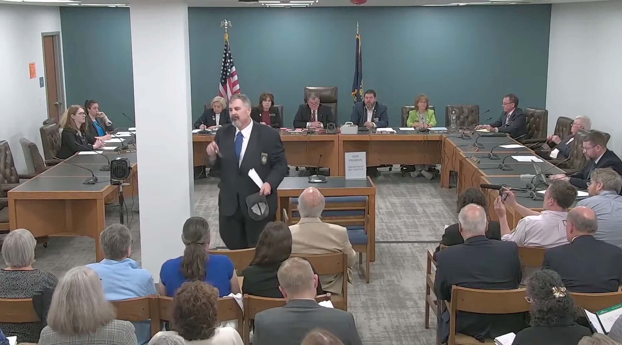 New Hampshire GOP state Rep. Travis Corcoran (center) walks out of his own disciplinary hearing for tweeting a “final solution” reference at a Jewish colleague, April 27, 2026. (Screenshot)