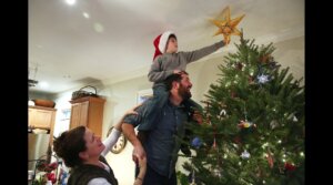 Karolyn Feeks Maws, who is Christian, her Jewish husband, Tony Maws, and their 8-year-old son Charlie Maws, decorate their Christmas tree with a homemade Star of David. (Pat Greenhouse/The Boston Globe via Getty Images)