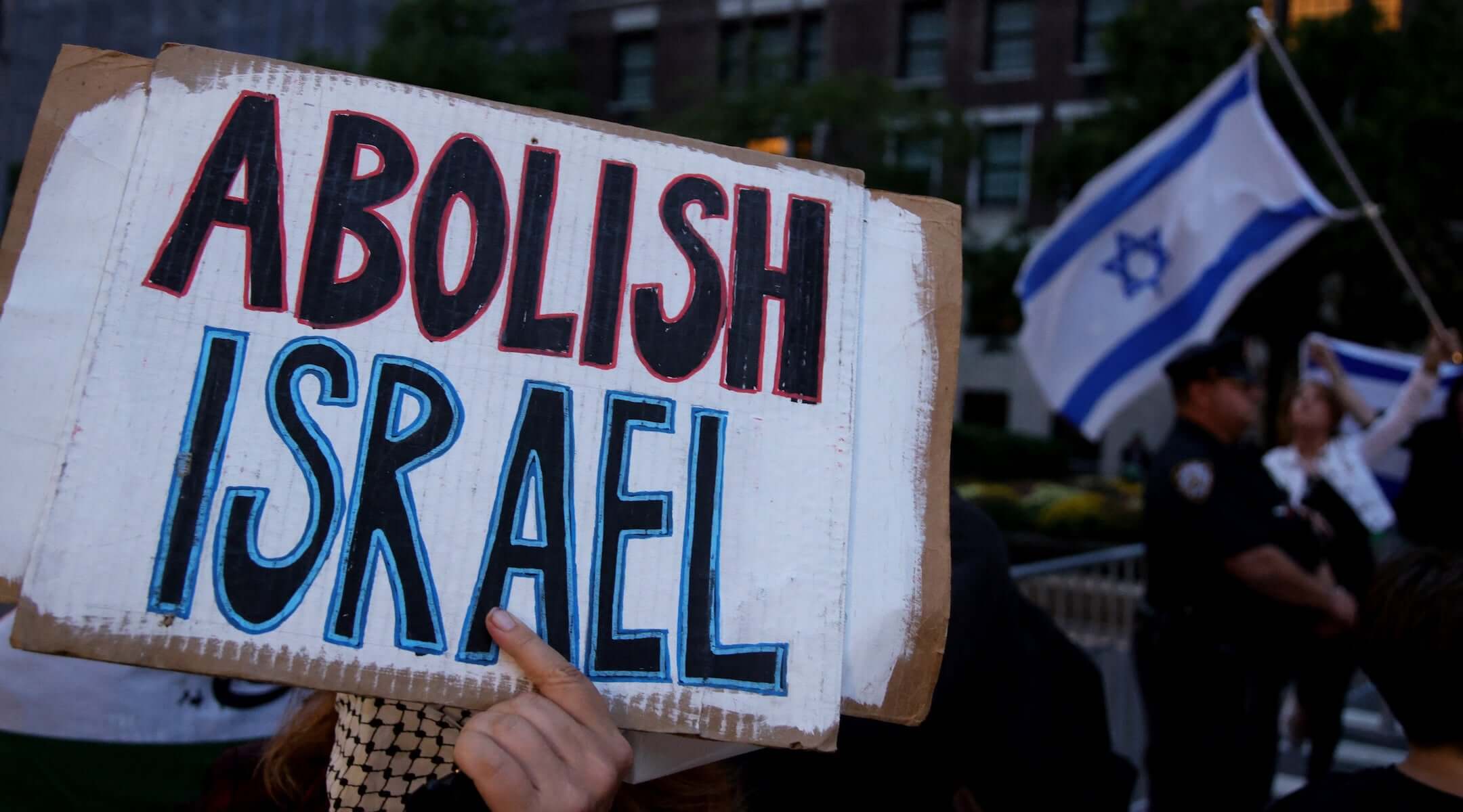 A pro-Palestinian activist holds a sign during the “Autonomous Noise Demonstration for Gaza” near supporters of Israel holding Israeli flagsoutside the hotel of Israel’s Prime Minister Benjamin Netanyahu in New York City on September 25, 2025. (Leonardo MUNOZ / AFP)