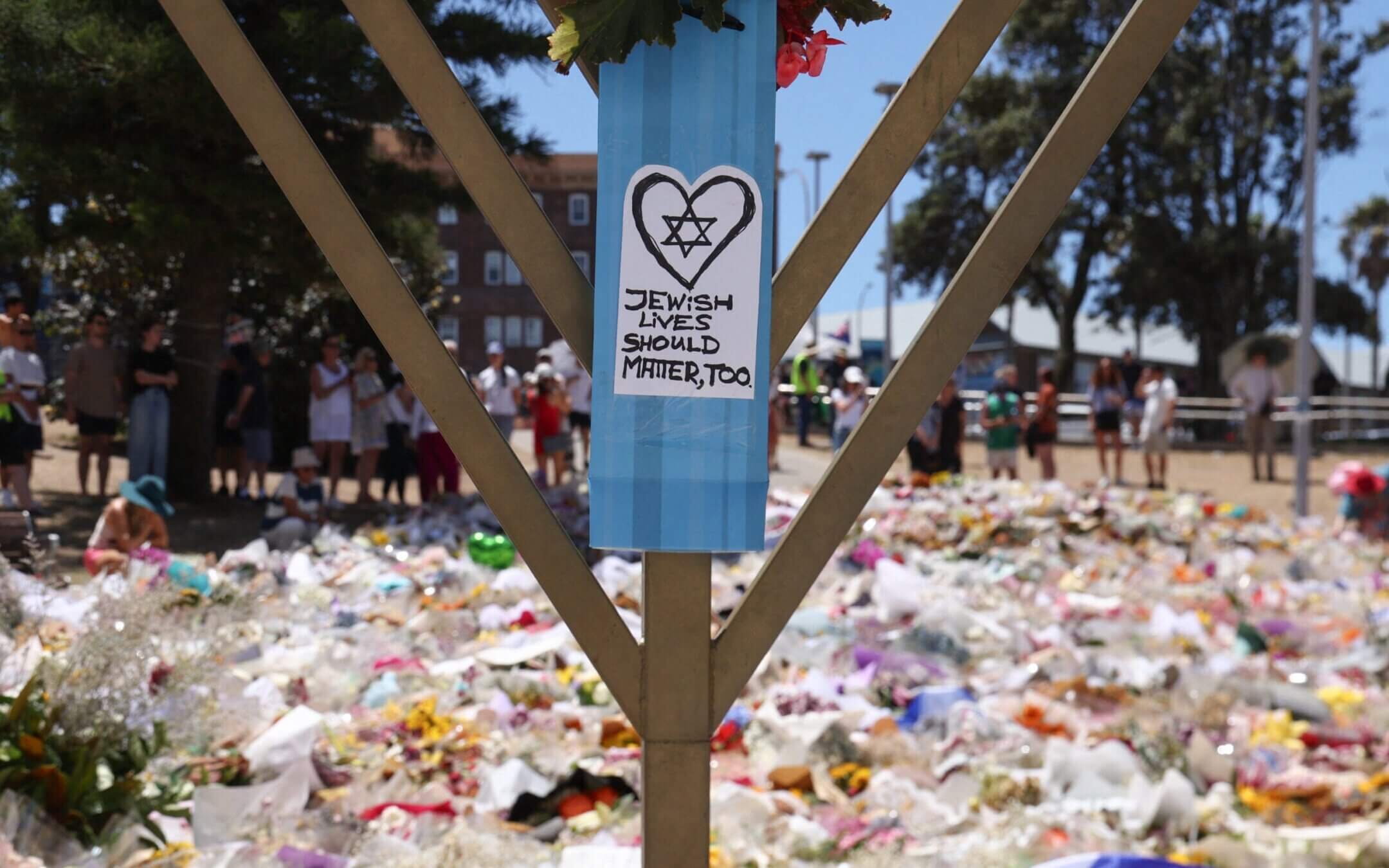 A sign reading “Jewish Lives Should Matter, Too” is seen at the floral tributes area outside Bondi Pavilion in Sydney on December 18, 2025, to honour victims of the Bondi Beach shooting. The attack at Bondi Beach on December 14 was one of the deadliest in Australian history. (Photo by DAVID GRAY / AFP via Getty Images)