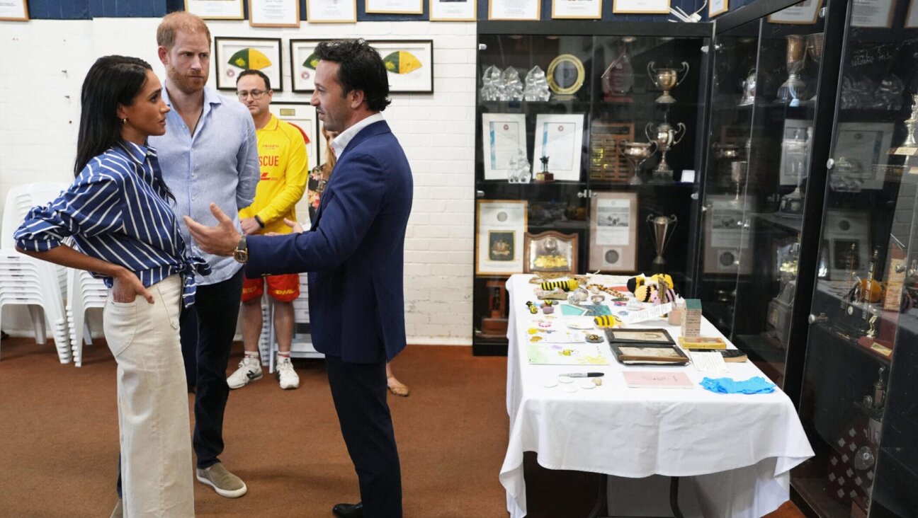 Britain’s Prince Harry, and his wife Meghan Markle speak with Elon Zizer, Bondi Beach Hanukkah attack survivor, during a meeting at the Bondi Surf Bathers’ Life Saving Club in Sydney, April 17, 2026. Artifacts from the aftermath of the shooting lie on the table behind Zizer.