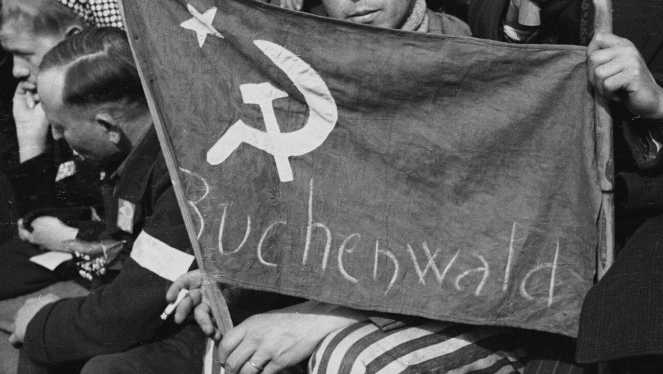A former prisoner from the Buchenwald concentration camp holds a flag with a hammer and a sickle in Paris, May 1, 1945. (Roger Viollet via Getty Images)