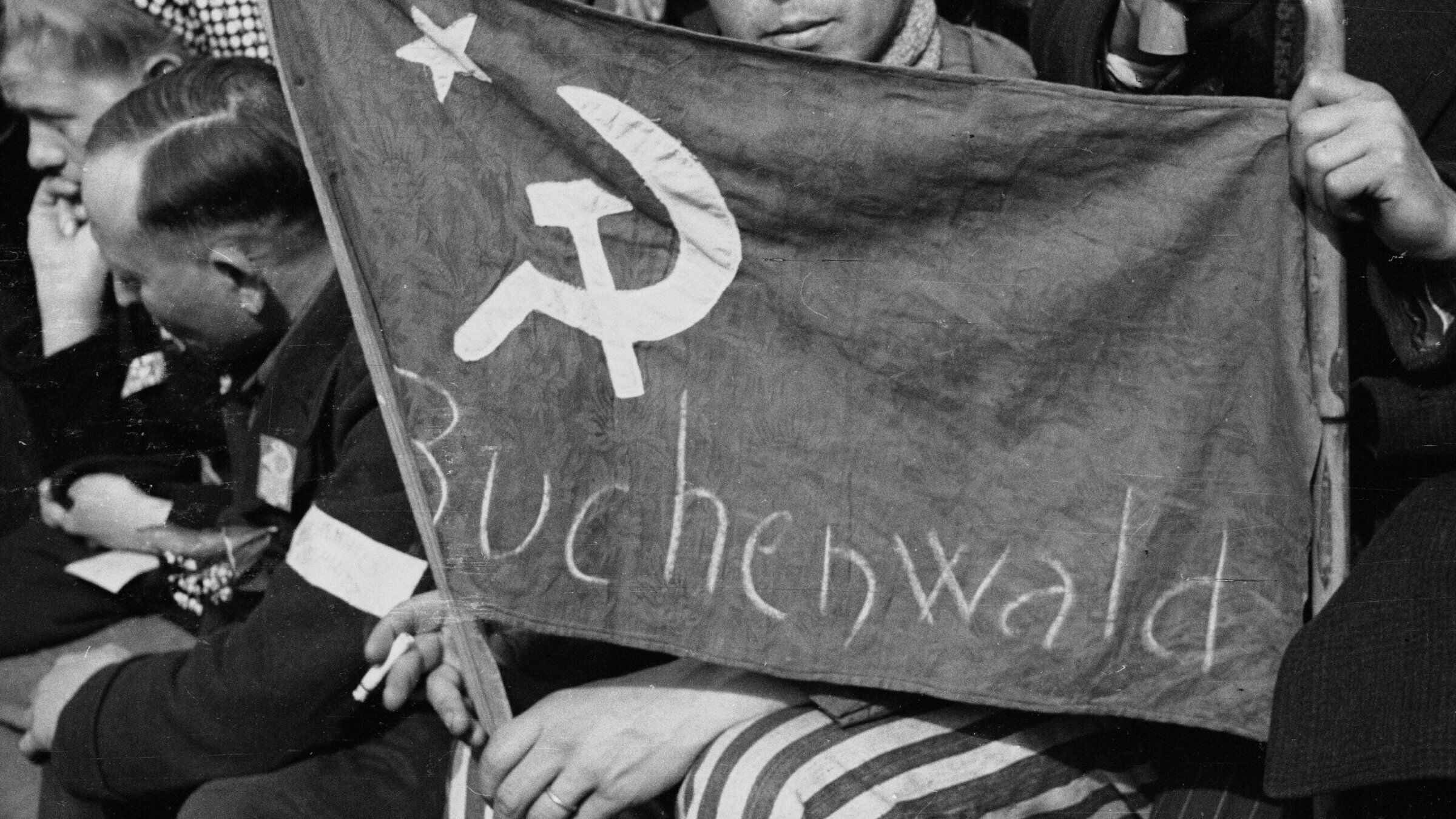 A former prisoner from the Buchenwald concentration camp holds a flag with a hammer and a sickle in Paris, May 1, 1945. (Roger Viollet via Getty Images)