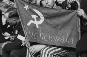 A former prisoner from the Buchenwald concentration camp holds a flag with a hammer and a sickle in Paris, May 1, 1945. (Roger Viollet via Getty Images)