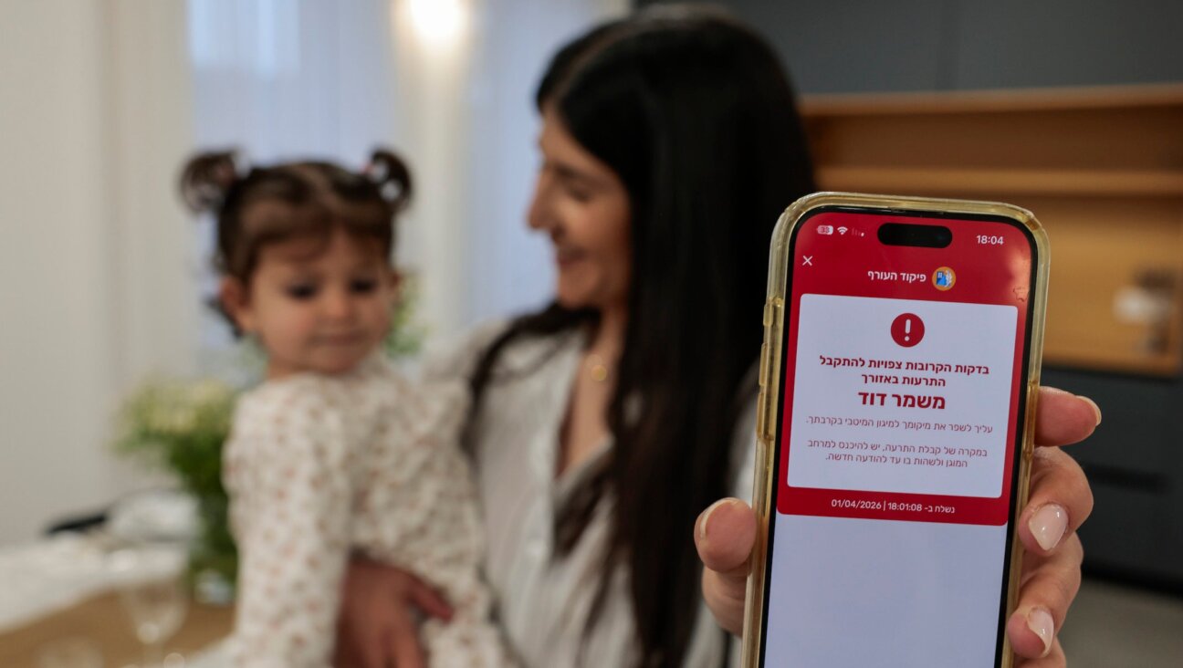 A woman shows a missile alert notification on her mobile phone as residents take cover indoors following missile fire from Iran toward Israel on the eve of the Passover, in Mishmar David, April 1. 2026.