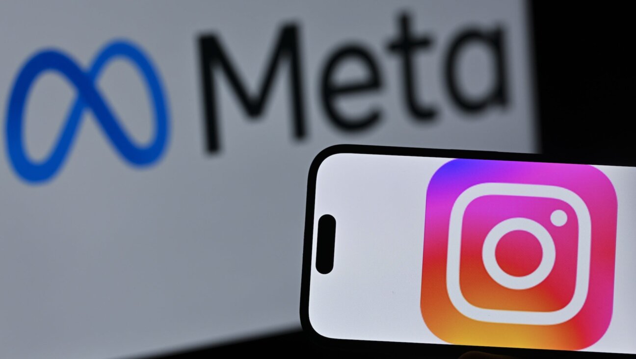The Instagram logo is displayed on a mobile phone screen in front of a computer screen displaying Meta logo on April 10, 2026.