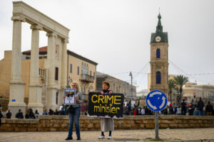 A woman holds a sign reading "crime minister" at a protest against the government's handling of violence against Israeli Arabs on Feb. 10 in the Jaffa area of Tel Aviv, Israel.