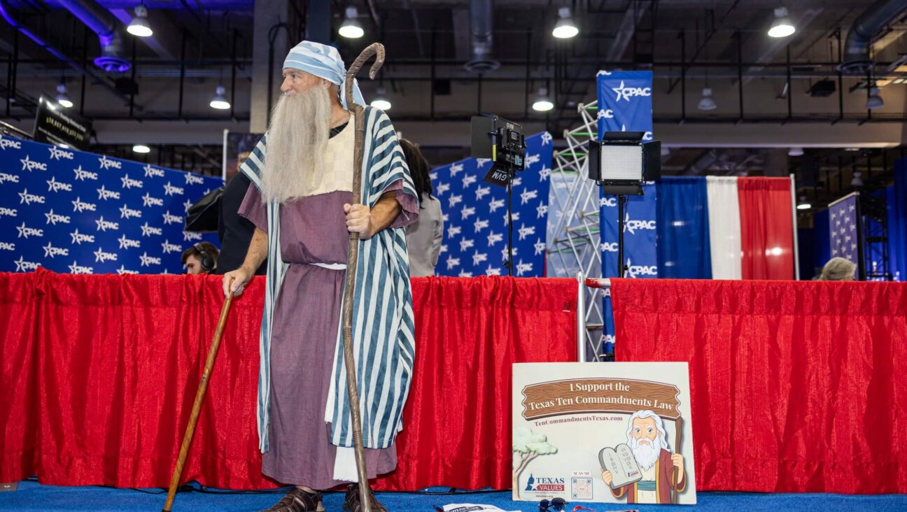 A man dressed as Moses stands next to a sign supporting the Texas Ten Commandments law during the Conservative Political Action Conference on March 27, amid spreading conservative efforts to display the Ten Commandments in civic institutions.