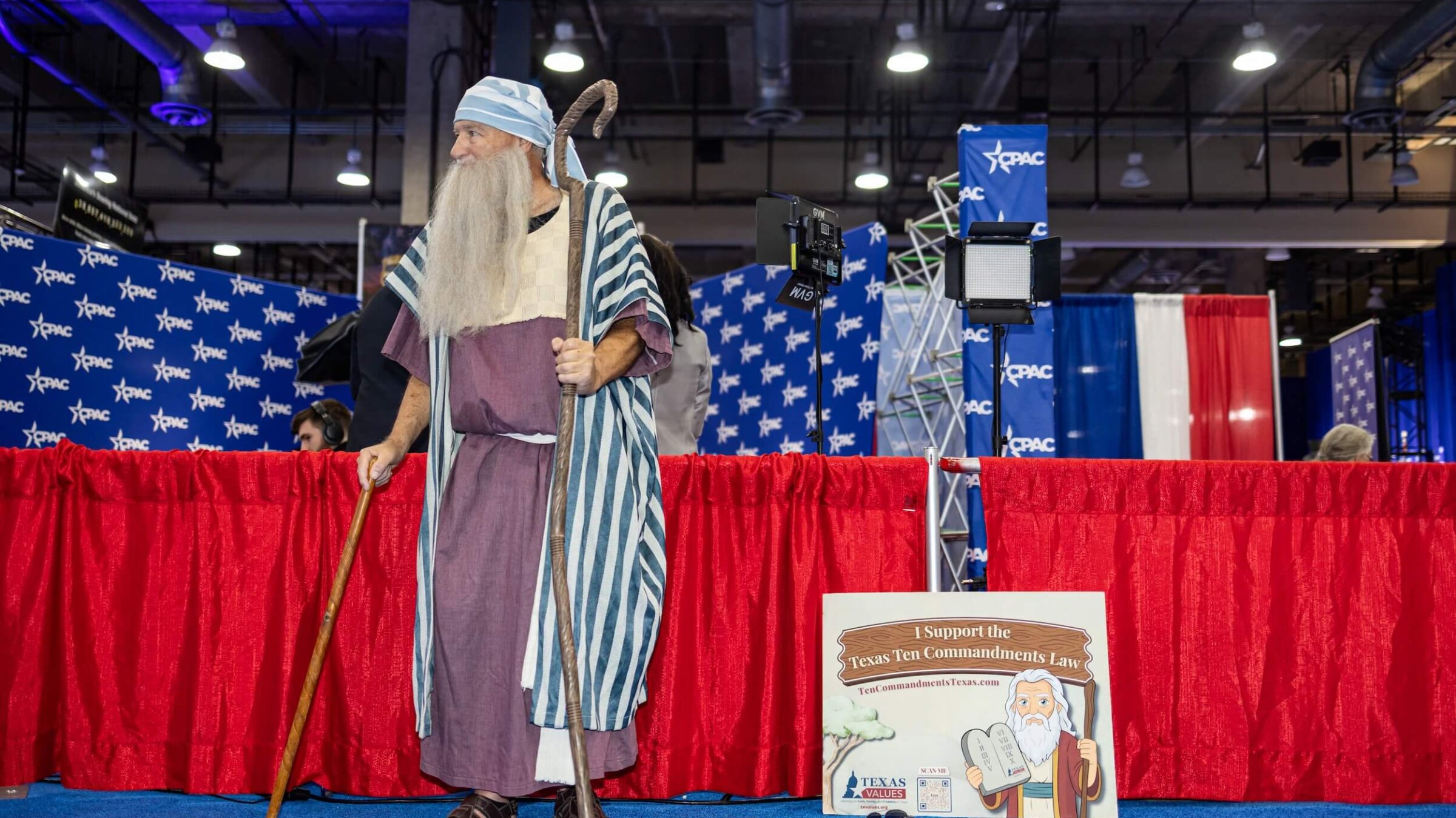 A man dressed as Moses stands next to a sign supporting the Texas Ten Commandments law during the Conservative Political Action Conference on March 27, amid spreading conservative efforts to display the Ten Commandments in civic institutions.