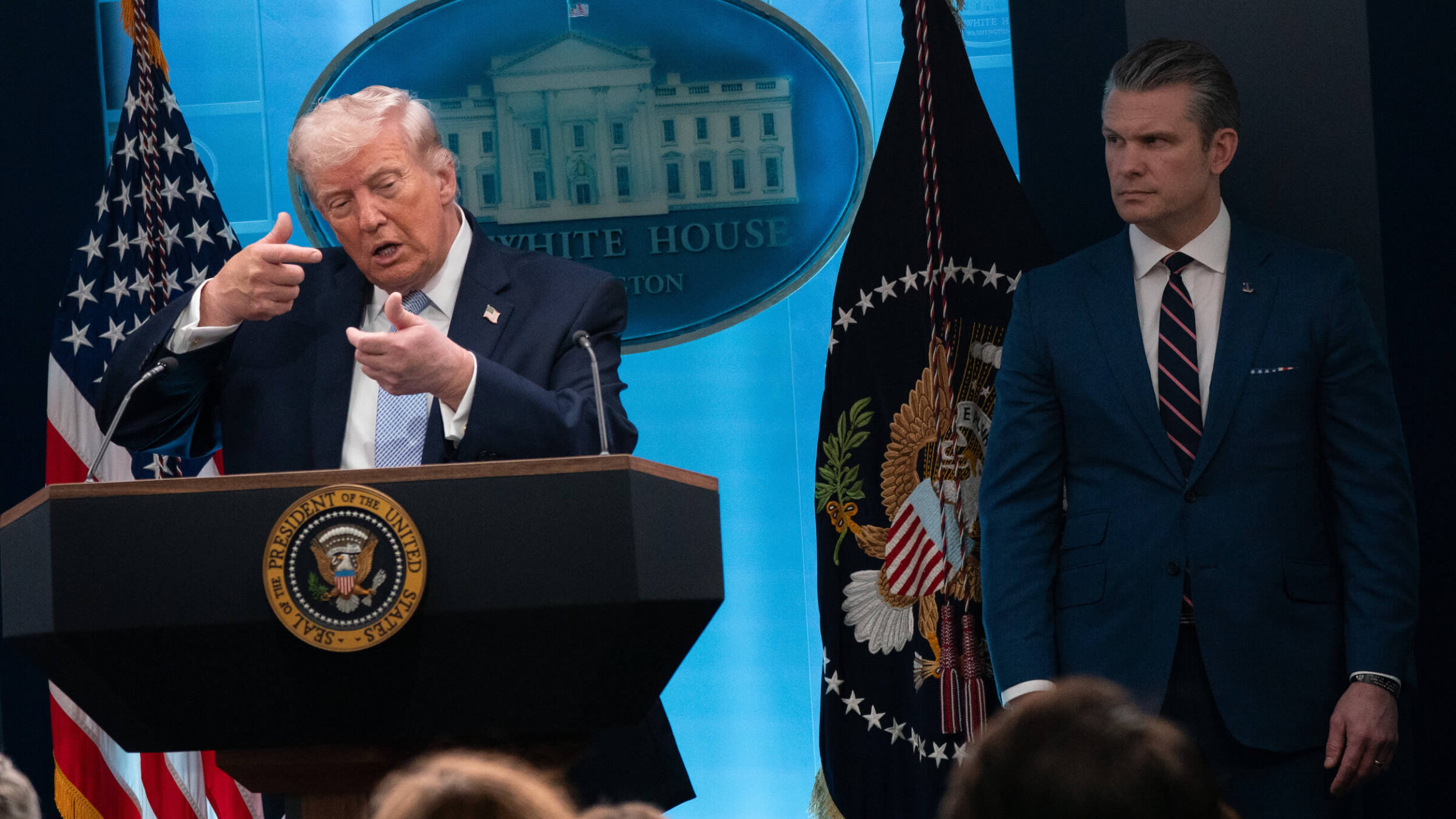President Donald Trump mimics firing a rifle while speaking to reporters at a briefing on Monday, April 6, at the White House in Washington, D.C.