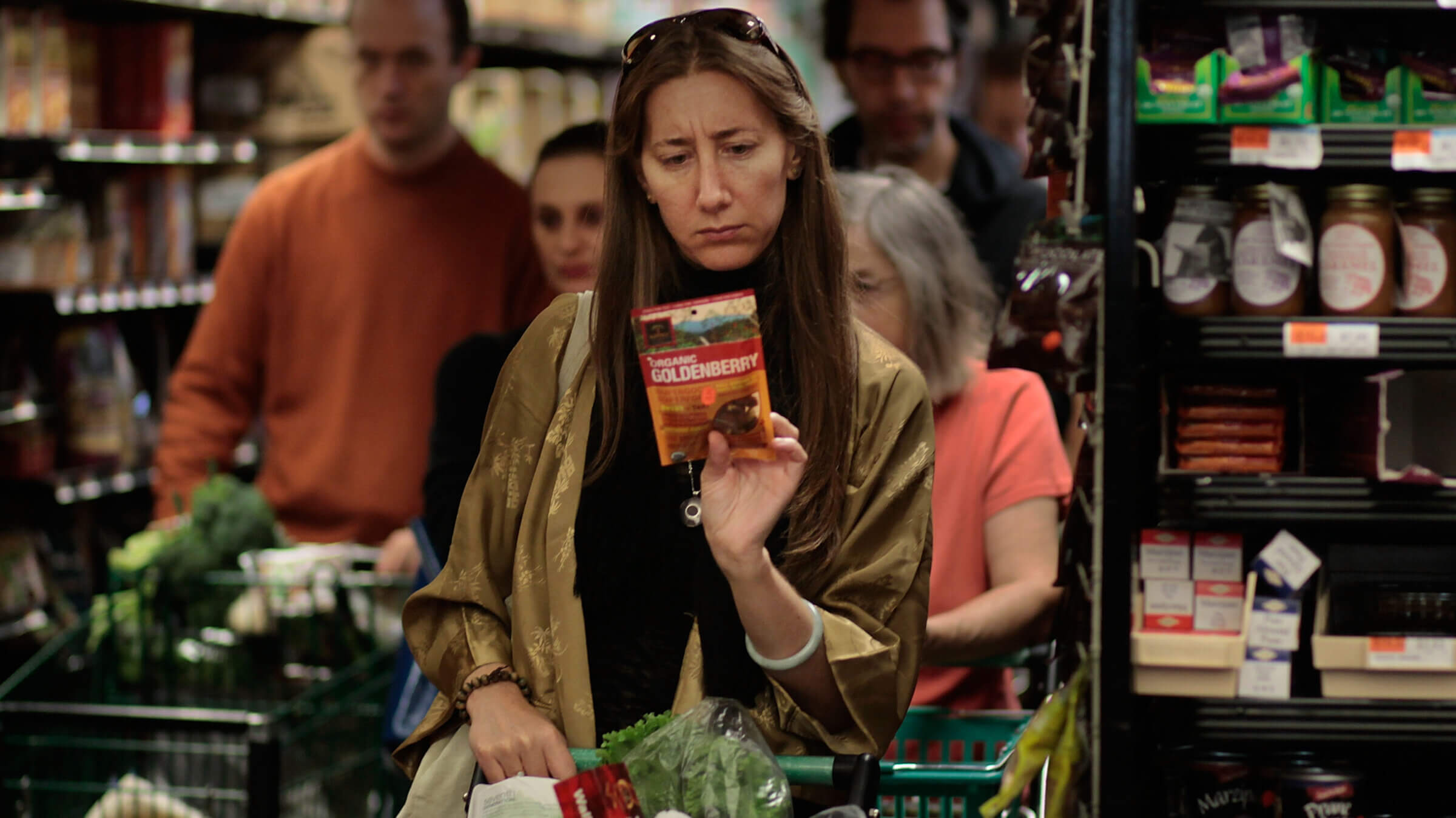 A woman carefully reading the label on a product at the Coop.