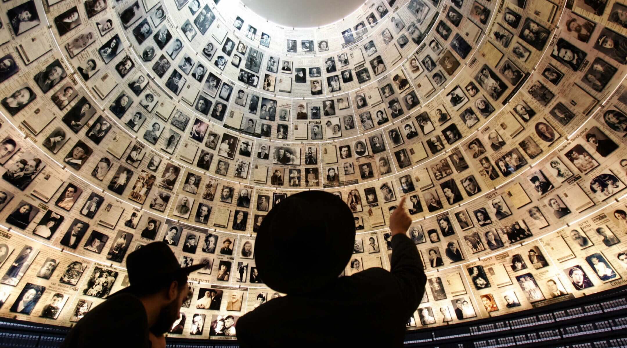 Jews look at the hundreds of photo portraits of Jews who were killed during the Nazi Holocaust in the Hall of Names inside Yad Vashem in Jerusalem, Nov. 1, 2005. (Menaham Kahana / AFP via Getty Images)