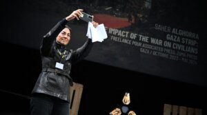 A representative of the Palestinian photographer Saher Alghorra takes a picture as Alghorra receives the 'Young Reporter Trophy' during the 2024 Prix Bayeux Calvados-Normandie in France, Oct. 12, 2024.