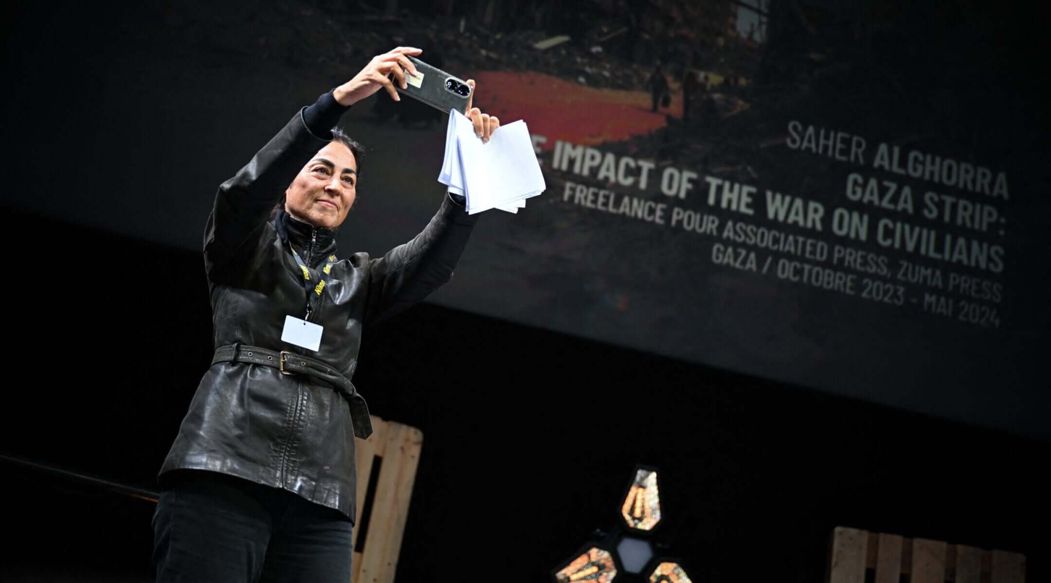 A representative of the Palestinian photographer Saher Alghorra takes a picture as Alghorra receives the 'Young Reporter Trophy' during the 2024 Prix Bayeux Calvados-Normandie in France, Oct. 12, 2024.