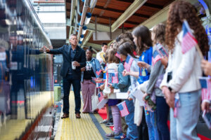 Students gather to welcome one of the events in the nation's celebration of it's 250th birthday, a "freedom 250" train.