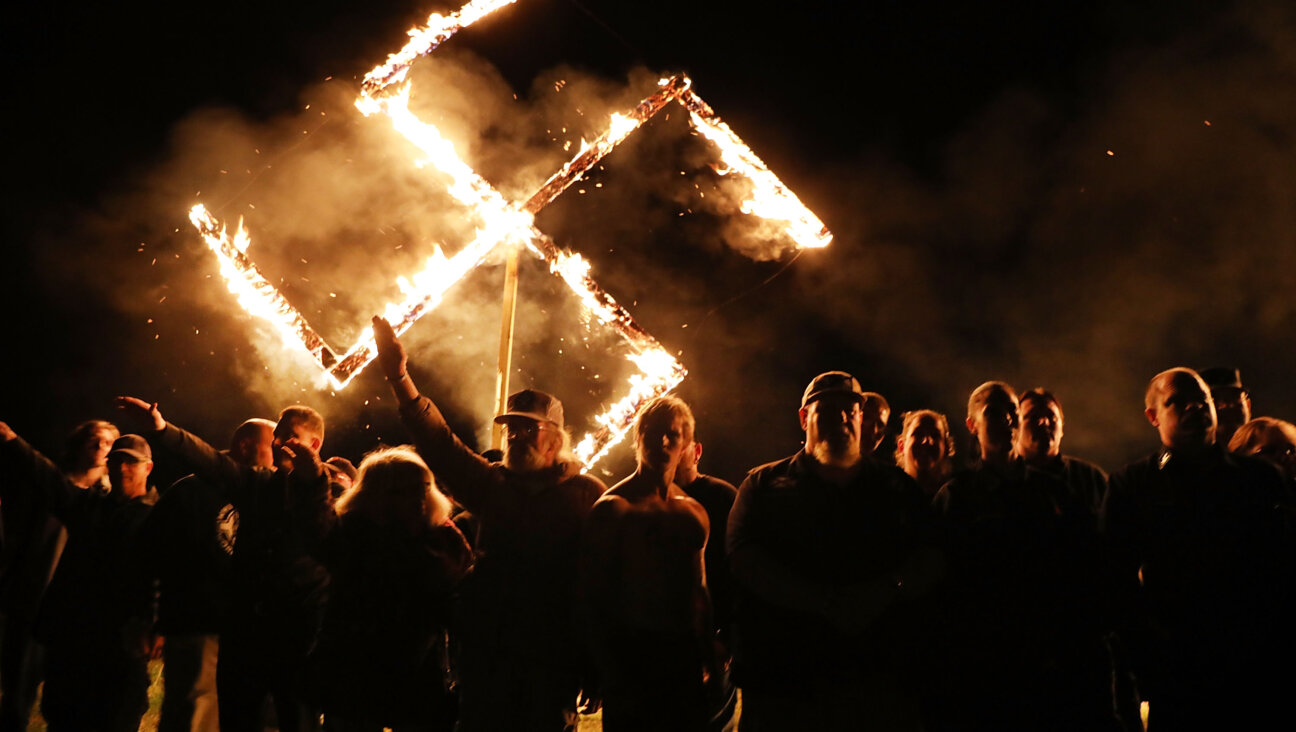 Members  of the National Socialist Movement, one of the largest neo-Nazi groups in the US, hold a swastika burning after a rally on April 21, 2018 in Draketown, Georgia.