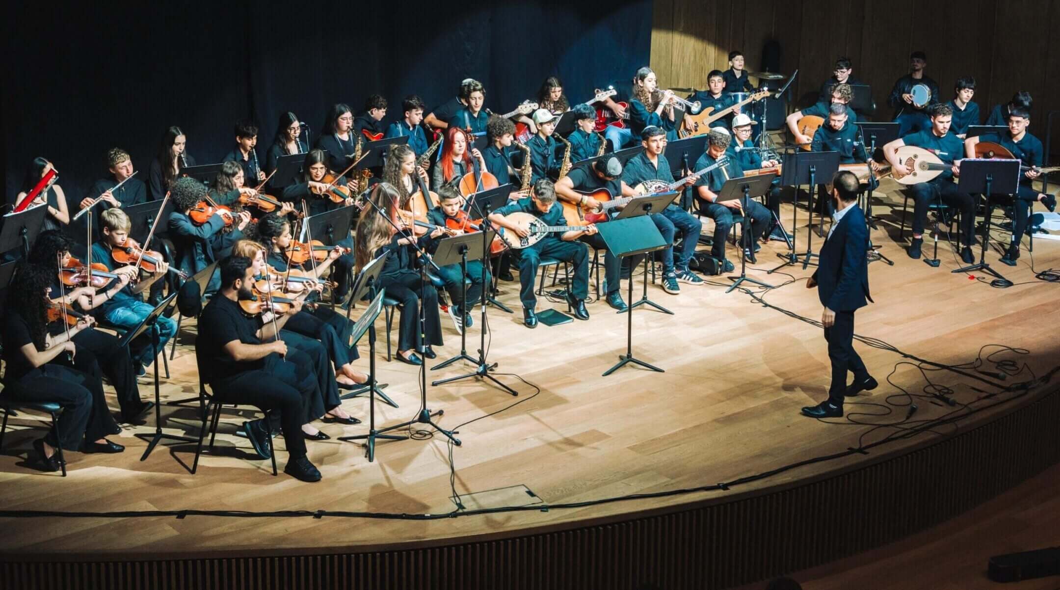 Tom Cohen conducts the youth program of The Jerusalem Orchestra East & West in Tel Aviv, May 2026. (Yaakov Buta)