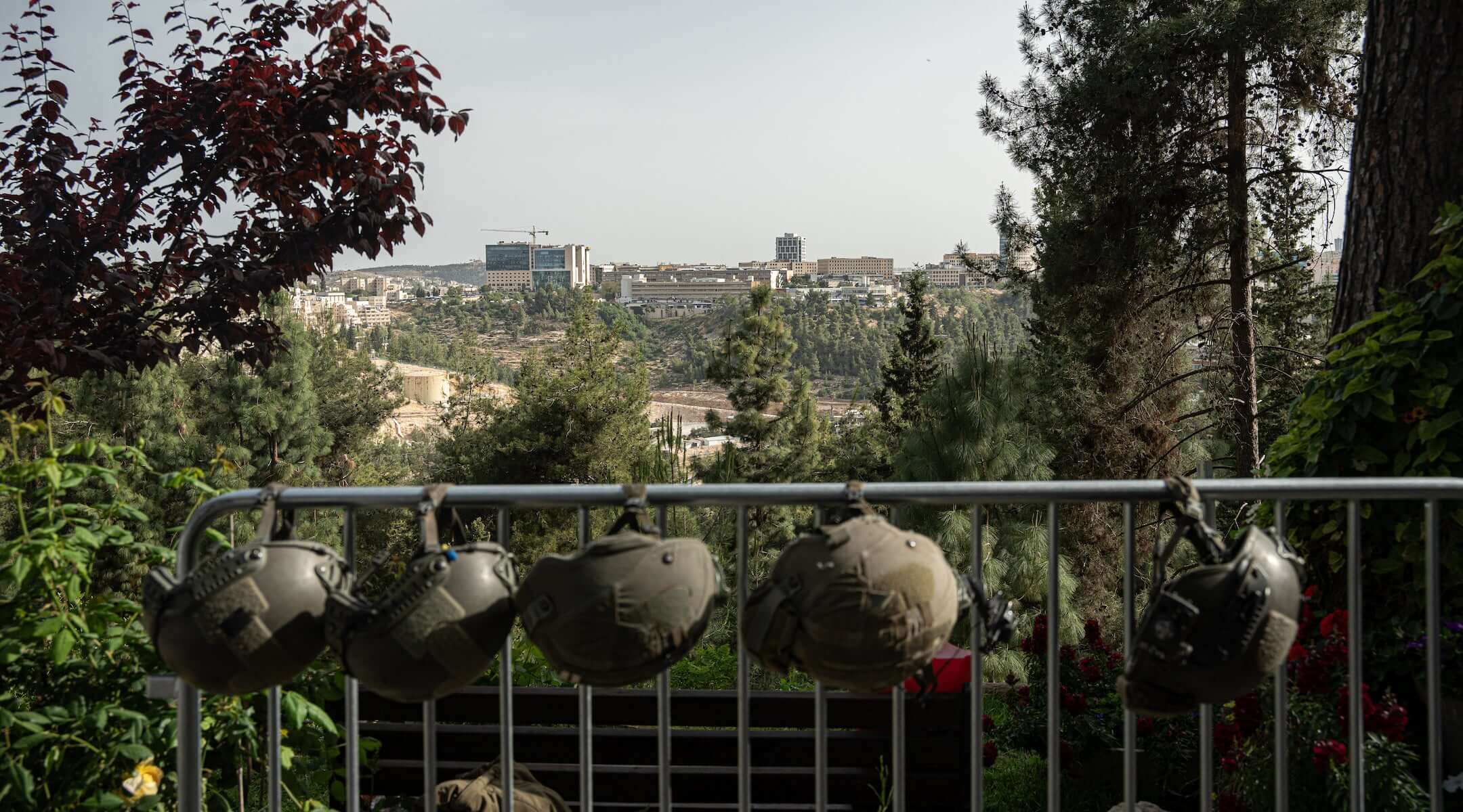 IDF soldiers’ helmets are hung from a rail, with Jerusalem in the background, on Israel’s Memorial Day on April 30, 2025 in Jerusalem, Israel. (Ori Aviram / Middle East Images / Middle East Images via AFP)