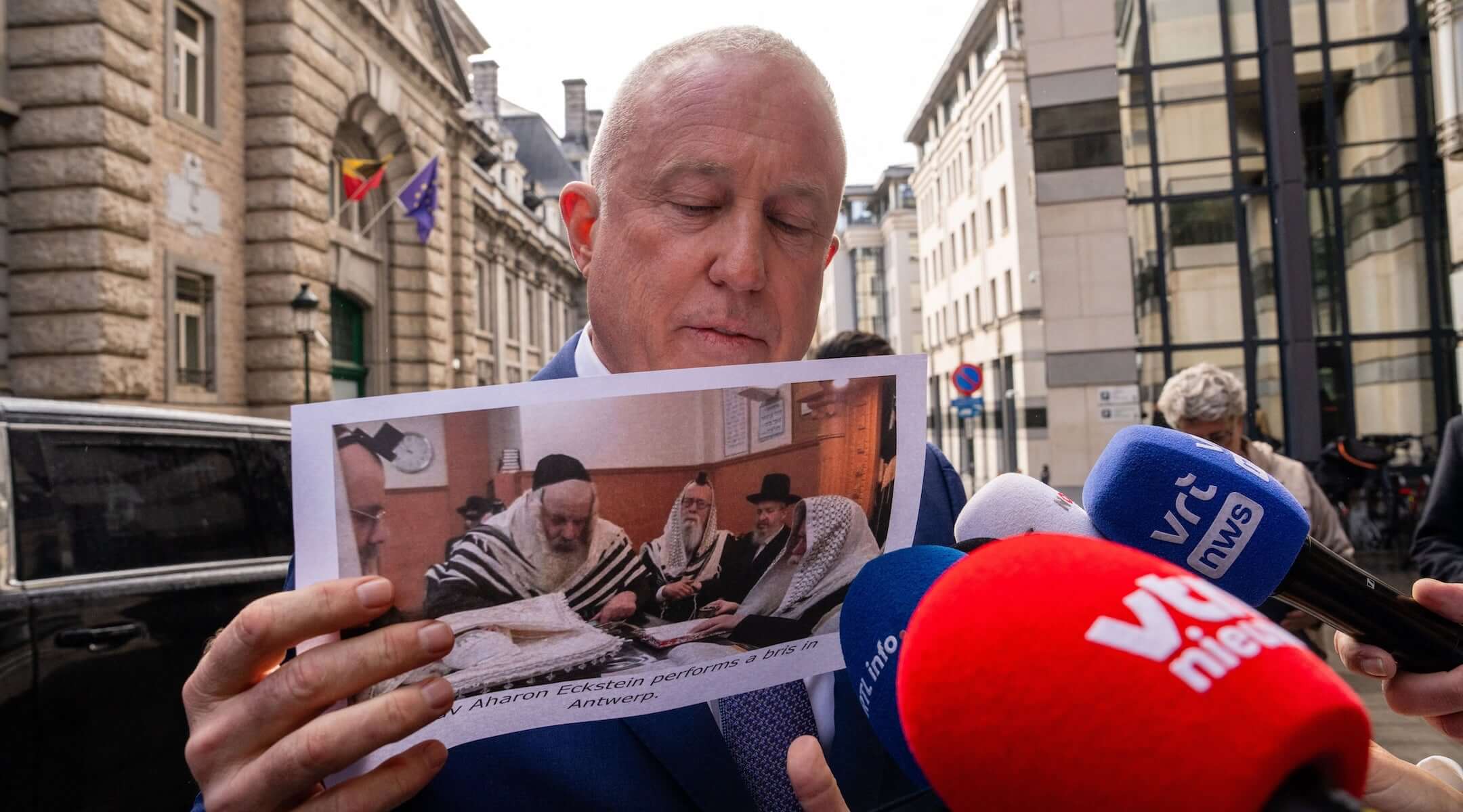 U.S. ambassador to Belgium Bill White shows an image of a ritual circumcision, as he arrives for a meeting at the offices of the Foreign Affairs department of the Federal Government in Brussels on Feb. 17, 2026.