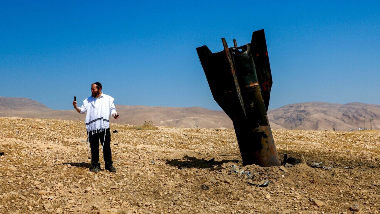 An Israeli man takes a selfie with the wreckage of an intercepted Iranian missile that landed near the West Bank city of Jericho.
