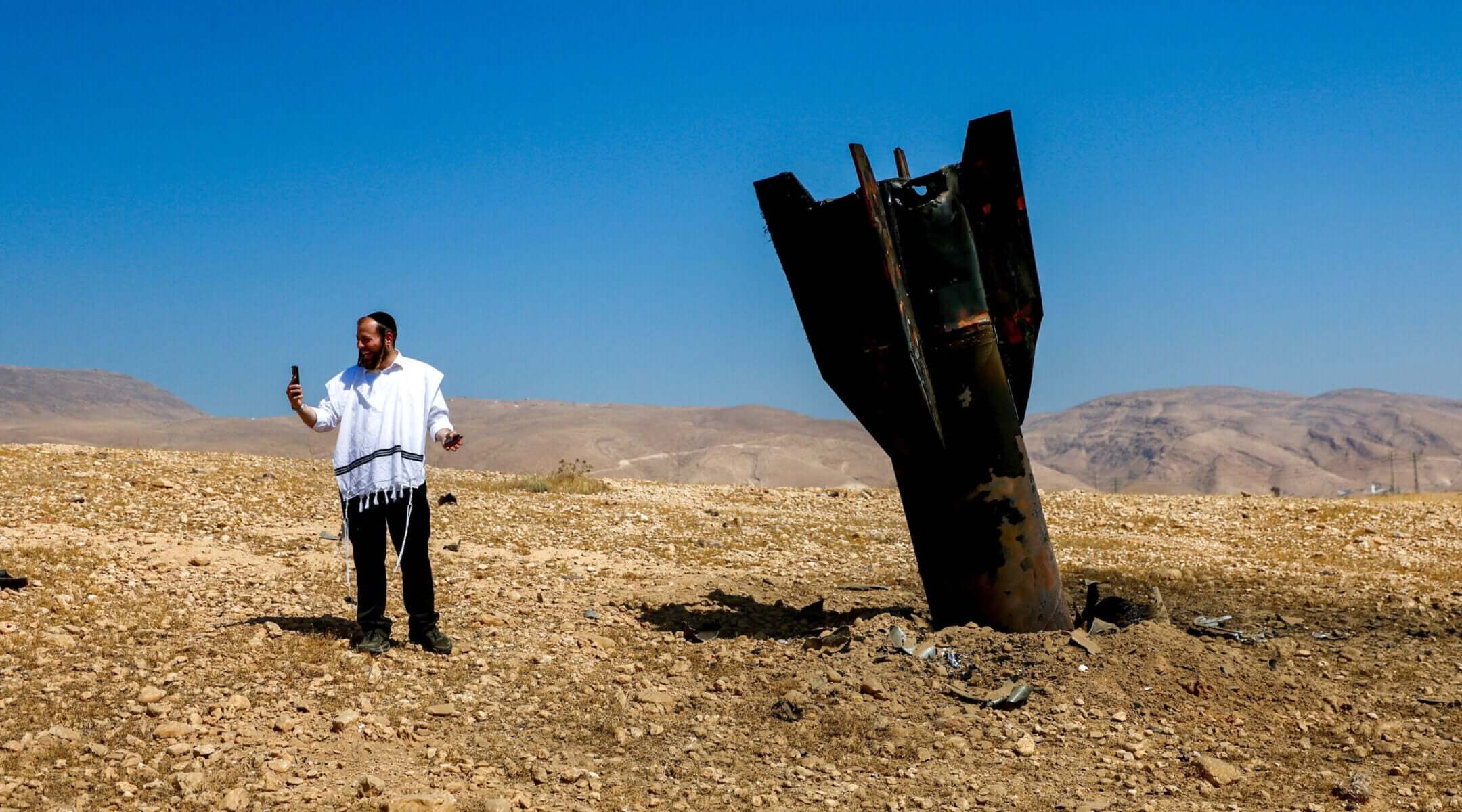 An Israeli man takes a selfie with the wreckage of an intercepted Iranian missile that landed near the West Bank city of Jericho.