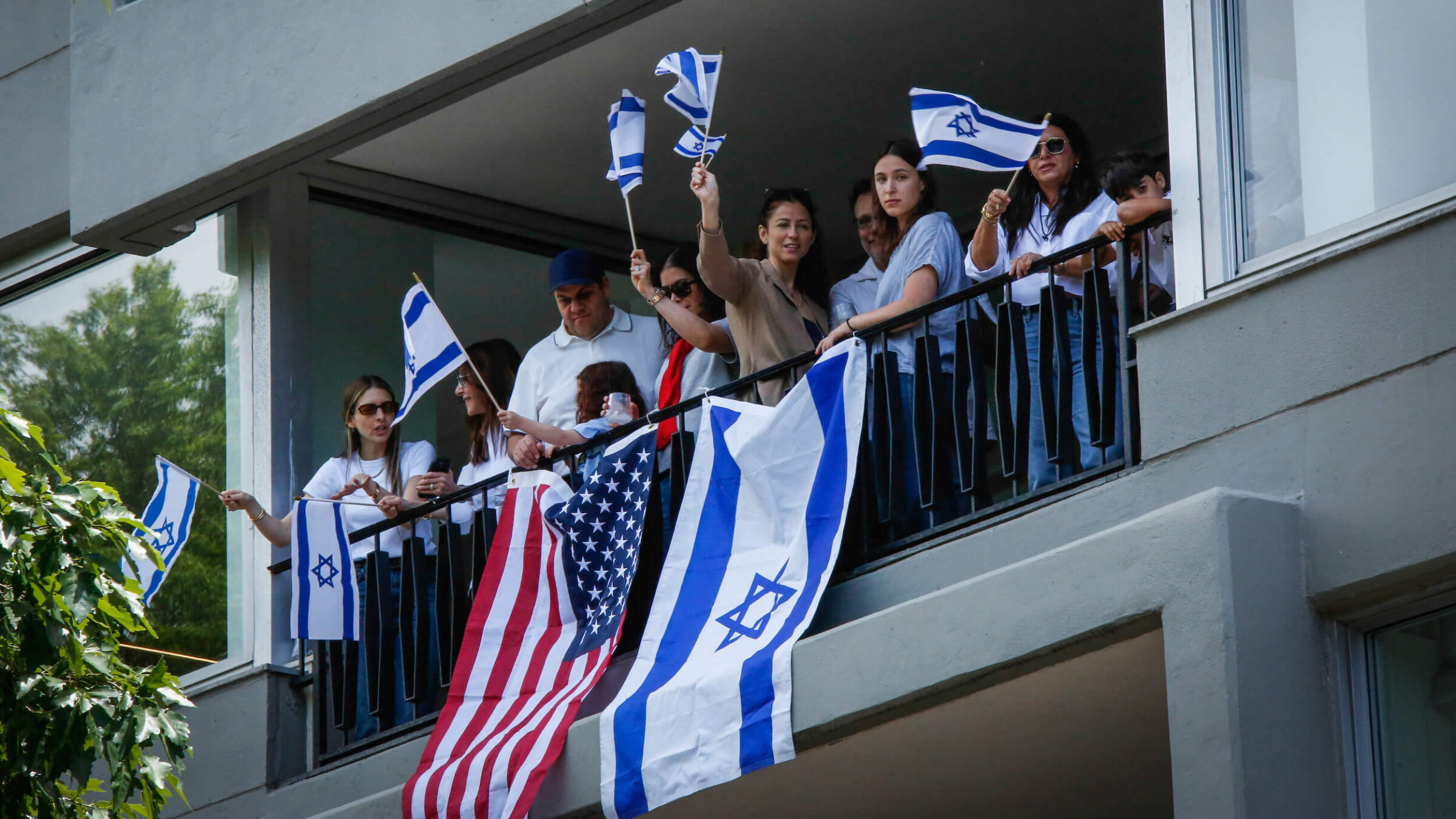 People wave Israeli and United States flags from a balcony on Manhattan's Fifth Avenue as they watch the Israel Day Parade on May 31.